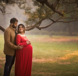 couple poses for pregnancy photosession in park